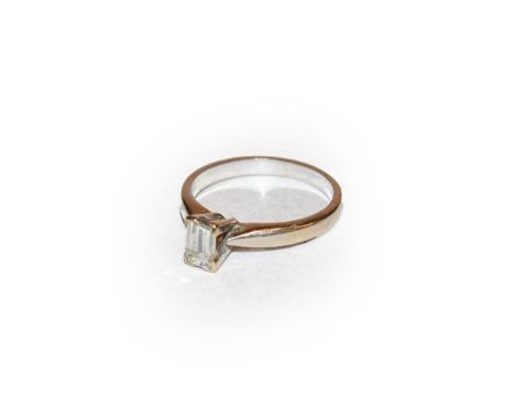An 18 carat white gold diamond solitaire ring, the step cut diamond in a four claw setting, to a tapered shoulder plain polis
