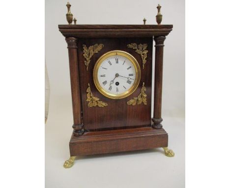 A mahogany cased mantle clock with turned finials, circular dial flanked by oak leaves and four turned columns, standing on l