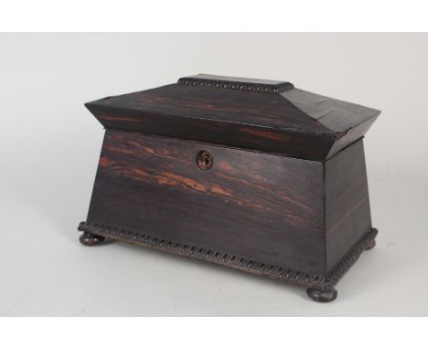 A 19th Century Coromandel tea caddy of sarcophagus form with twin lidded compartments, beaded banding and raised on four bun 