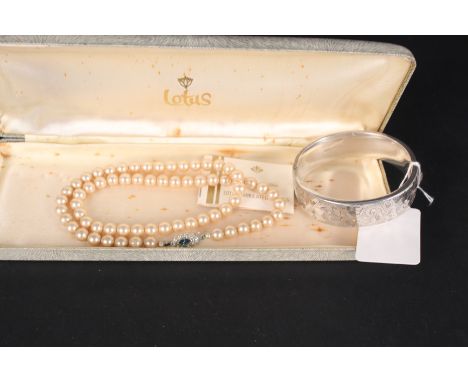 A silver bangle with engraved detail, together with a simulated pearl necklace in lotus box