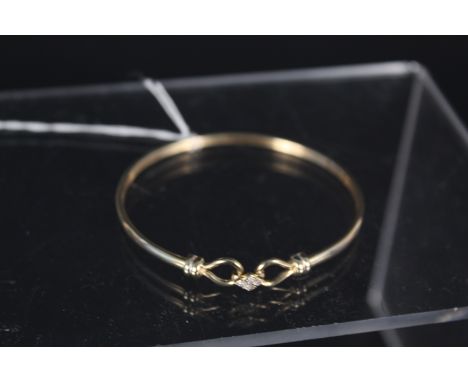 A 9ct gold bangle, the clasp set with four diamonds