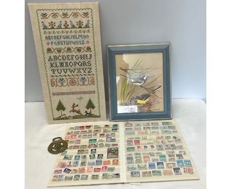 Needlework sampler, framed print of birds, World and British stamp album and Winston a Churchill horse brass (4)