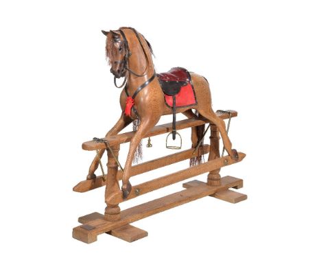 An oak rocking horse, dated 2005, by Stevenson Brothers, with chestnut mane, red leather and suede paneled saddle, on a trest