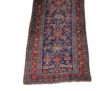 A Caucasian runner, the blue field decorated with flowerheads and foliate motifs, within madder and blue borders, approximate