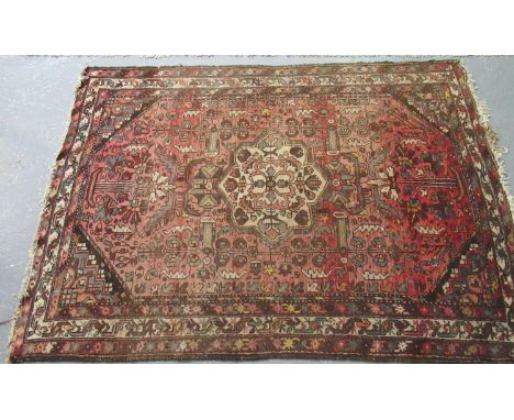 Middle Eastern design salmon and brown ground carpet with central floral medallion flanked by stylised flower heads and simil