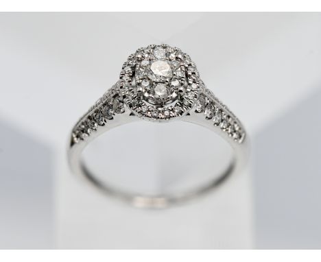 An oval shaped diamond cluster ring, set in 18ct white gold, size R.