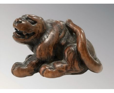 A Japanese carved hardwood netsuke of a recumbent tiger, late-19th century, unsigned, length 4cm. 