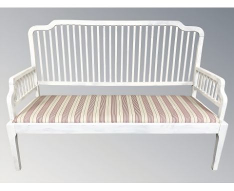 An early 20th century painted bench with striped cushion, length 153 cm.