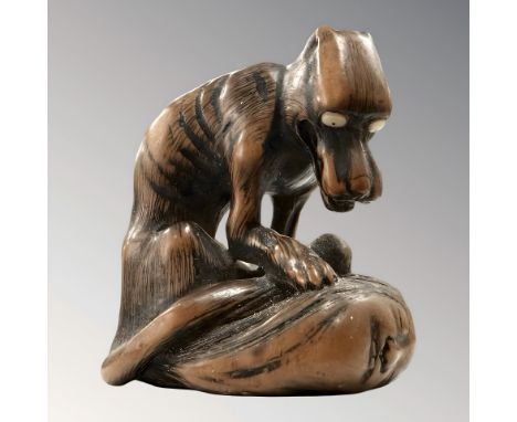 A Japanese Toyomasa School carved hardwood netsuke in the form of a starving wolf standing over a severed head, late-19th cen