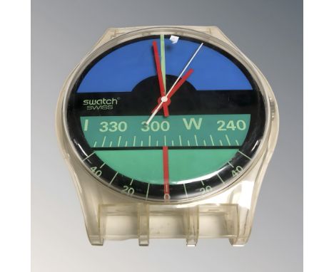 A quartz wall clock in the form of a swatch watch, width 30 cm.