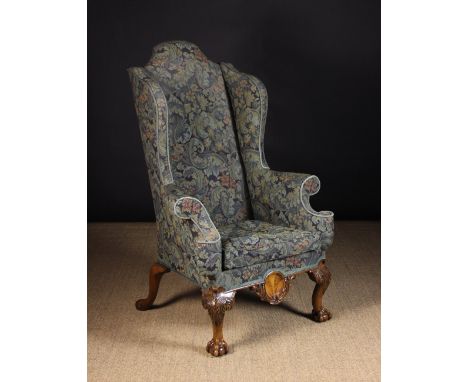 A Fine Early 20th Century Queen Anne Style Wingback Armchair. The tall humped back, winged sides, out-swept scroll arms, upho