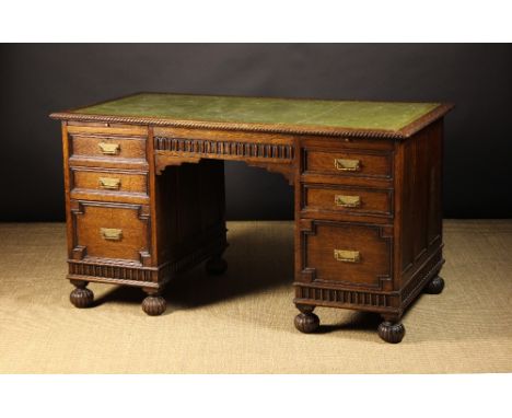 An Oak Pedestal Desk.  The top having a carved ropetwist edge and a green leather insert with a tooled border. The pedestals 