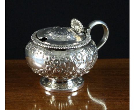 A Small Georgian Silver Mustard Pot hallmarked London 1802 and decorated with embossed & chased flowers above a reeded base a