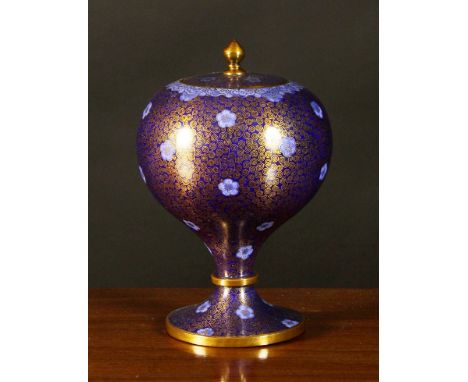 A Cloisonné Pedestal Urn. The globular vessel having a finial knopped lid decorated with fine gilt scrollwork on a dark blue 
