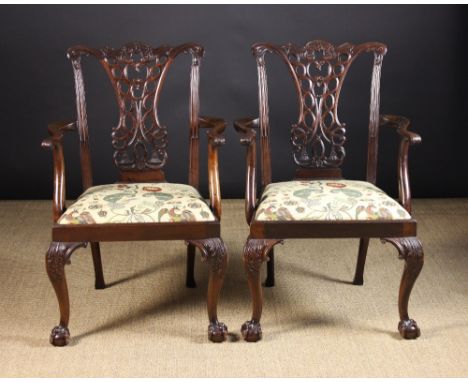 A Pair of Chippendale Style Carved Mahogany Open Armchairs.  The broad pierced back splats carved with entwined ribbons and t