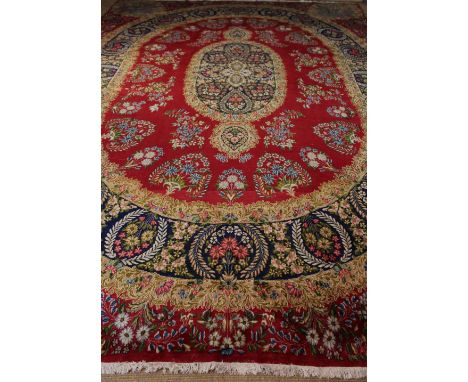 A Large Good Quality Persian Kirman Carpet woven with panels on flowers and foliage on a claret ground and measuring 16 ft 8 