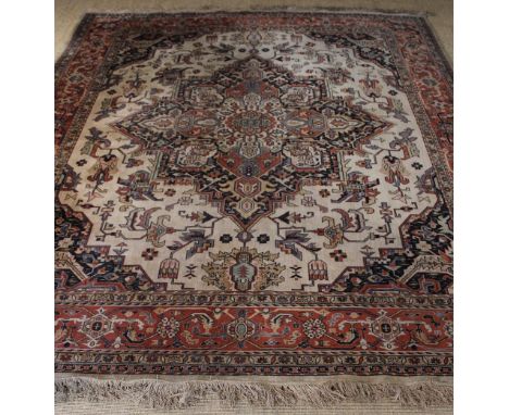 An Old Machine Woven Carpet of Persian Design having a central red ground medallion on an ivory field decorated with floral m