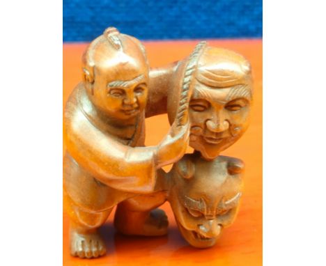 Japanese hand carved root wood netsuke of Oni Mask Seller. Signed to the foot. [4.5cm high] 