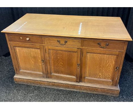 Antique heavy light oak library study desk- fitted with three drawers and three doors to each side. Raised on a plinth base. 