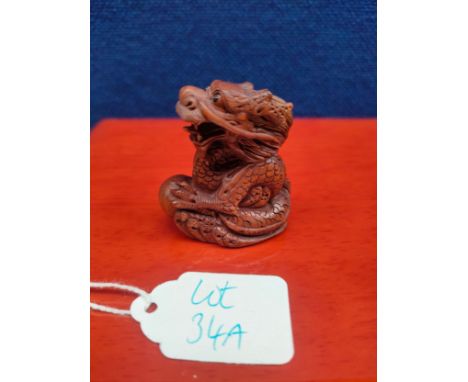 Japanese hand carved root wood netsuke of a Dragon holding a sphere. Fitted with black bead eyes, Signed to the underside. [4