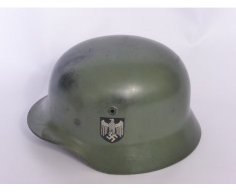 A WWII German Nazi Helmet, model M1940, with original paint and Nazi insignia to the side markings, lacking the liner, marked