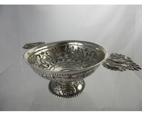 A Circa 19th Century Continental Quaich, the vessel embossed with birds in relief with fret work handles on pedestal foot, m.