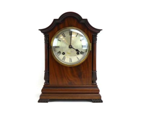 An early 20th century mantel timepiece, the circular silvered dial with black Roman numerals within a mahogany case of archit