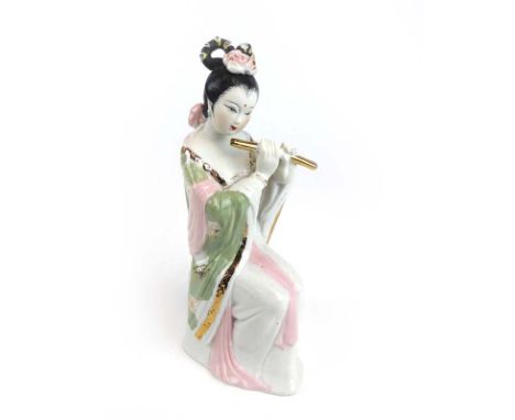 A porcelain figure modelled as a seated female playing the flute in the Chinese manner, h. 24.5 cm (af) CONDITION REPORT: Hea