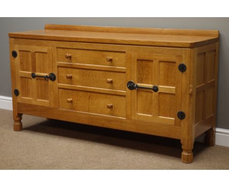 'Mouseman' oak sideboard with adzed top, three centre drawers and two cupboards, panelled, wrought iron fixtures and fittings