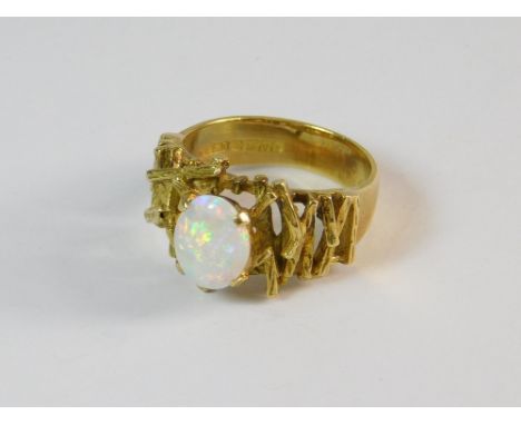 OPAL RING. An 18ct. gold solitaire opal ring, the shoulders of textured random batons. Size M.  Please note that all items in