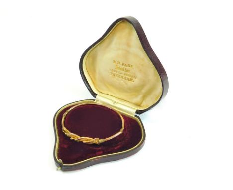 GOLD BANGLE. A 9ct. gold hinged bangle of beaded interwoven design (in heart shaped box, possibly not original).  Please note