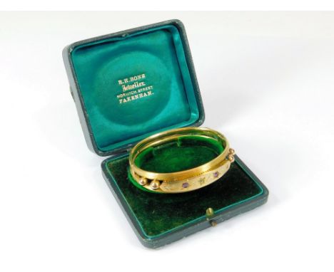 EDWARDIAN BANGLE. An Edwardian 9ct. gold hinged bangle, the front set with two rubies & three diamonds. Birmingham 1902. Appr