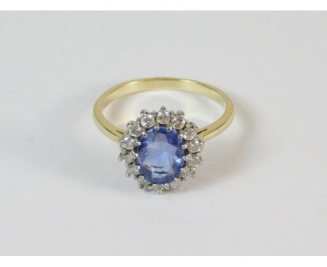 CEYLON SAPPHIRE. A bespoke 18ct. gold ring, cluster set a Ceylon sapphire of approx. 1.55ct., within a border of 14 diamonds.