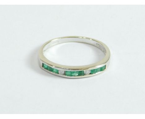 EMERALD RING. An 18ct. white gold ring, channel set with nine emeralds & two diamonds. Size L/M.  Please note that all items 