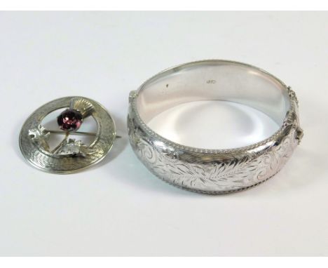 SILVER BANGLE ETC. A 1960's broad, hinged bangle, engraved 'Penny'. Also, a Scottish silver thistle brooch.  Please note that