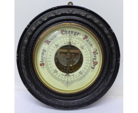 An aneroid barometer, R. McQueen & Son, Newcastle-on-Tyne in a carved ebonised circular frame