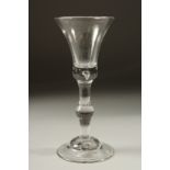 A GEORGIAN WINE GLASS with plain inverted bell bowl and knop stem. 7ins high.