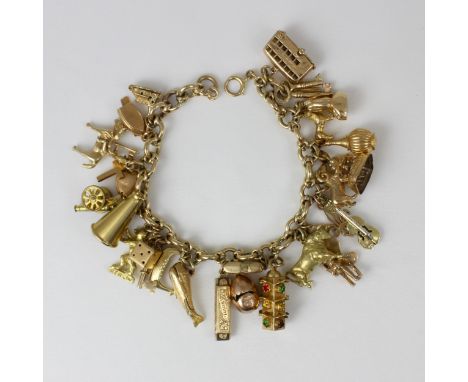 A 9ct yellow gold charm bracelet, the fancy trace link bracelet suspending twenty-seven yellow metal and gold-coloured charms