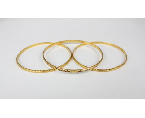A pair of yellow metal bangles, possibly Middle Eastern, the bangles with continuous engraved decoration, stamped possibly '8