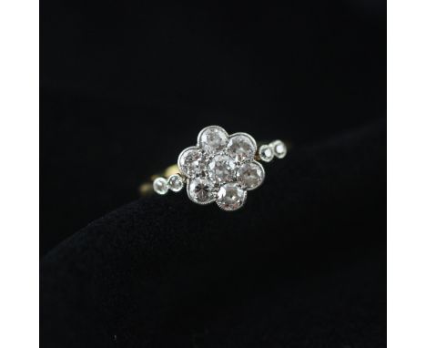 An early 20th century diamond cluster ring, the central old cut diamond within a surround of six mixed cut diamonds, set in w