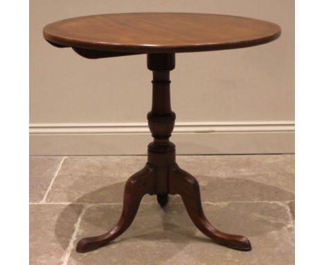 A George III mahogany tripod table, the circular tilt top upon a cup and baluster pedestal, extending to three cabriole suppo