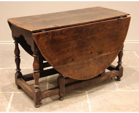 An 18th century oak gateleg dining table, the oval plank top above a shaped frieze, upon bobbin and block turned supports uni