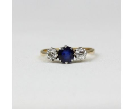 An early/mid 20th century sapphire and diamond three stone ring, the central cushion cut sapphire with old cut diamond to eac