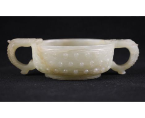 A Chinese Jade two handled cup, 18th century, of circular form and carved externally with three rows of studs, the body flank