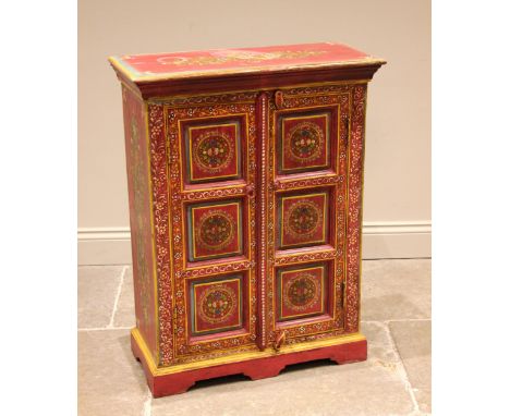 A painted Indian hardwood cabinet, finished in vibrant red and yellow colourways, the pair of three panelled doors opening to