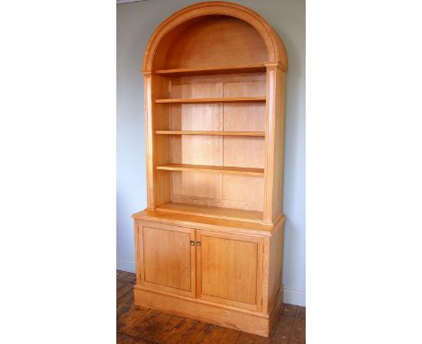 A light oak architectural alcove bookcase, late 20th century, the domed pediment over three adjustable shelves, upon the base