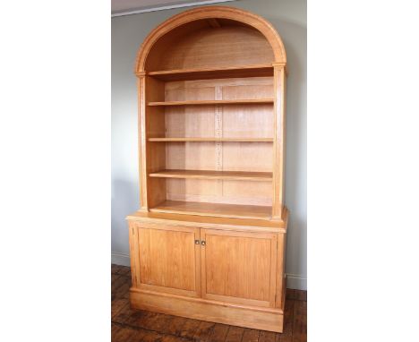 A light oak architectural alcove bookcase, late 20th century, the domed pediment over three adjustable shelves, upon the base