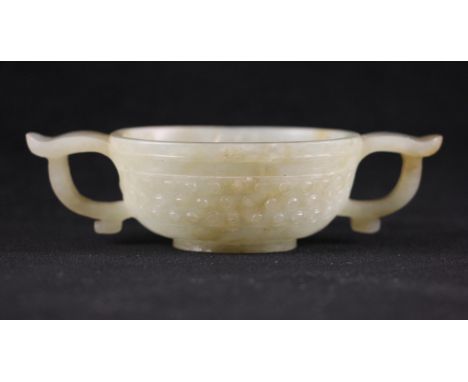 A Chinese Jade two handled cup, 18th century, of oval form and carved externally with three rows of studs, the body flanked b
