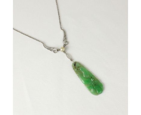 An early 20th century jade necklace, the openwork white metal stylised motifs leading to ‘pearl’ and carved jade panel, upon 