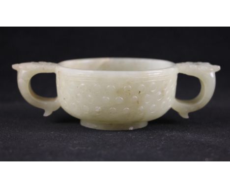 A Chinese Jade two handled cup, 18th century, of circular form and carved externally with three rows of studs, the body flank